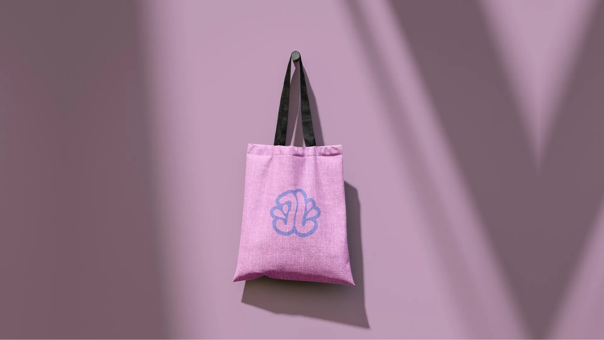 A pink canvas tote printed with the JellyLab logomark, hanging on a lilac wall.